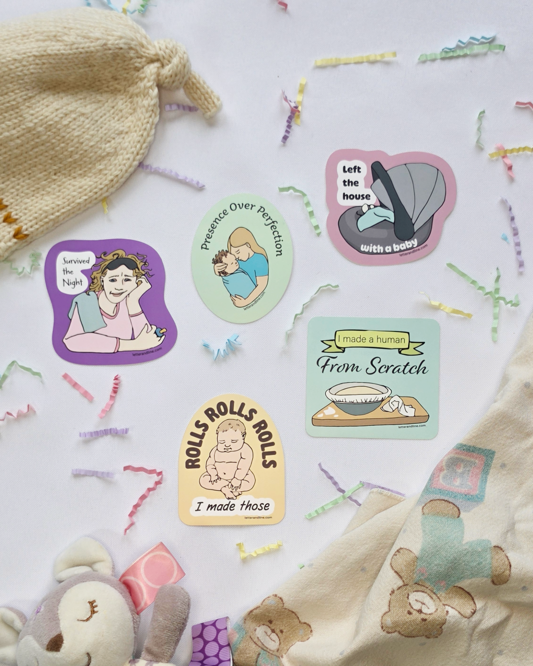 Five new parent milestone stickers styled with baby items including a knit hat, muslin swaddle, and stuffed animal — Survived the Night, Presence Over Perfection, Left the House with a Baby, Rolls Rolls Rolls I Made Those, and I Made a Human From Scratch
