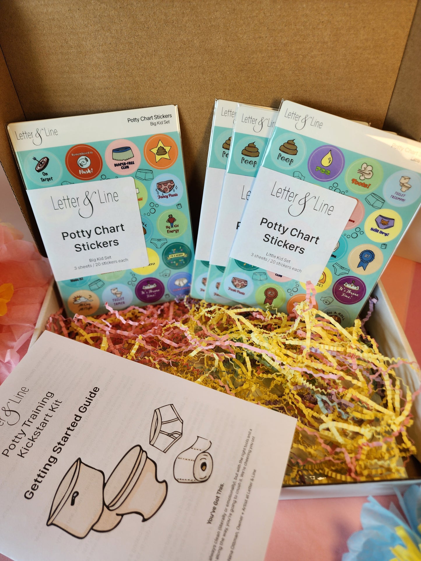 Open box showing toddler potty chart stickers, getting started guide, and colorful shredded paper filling.