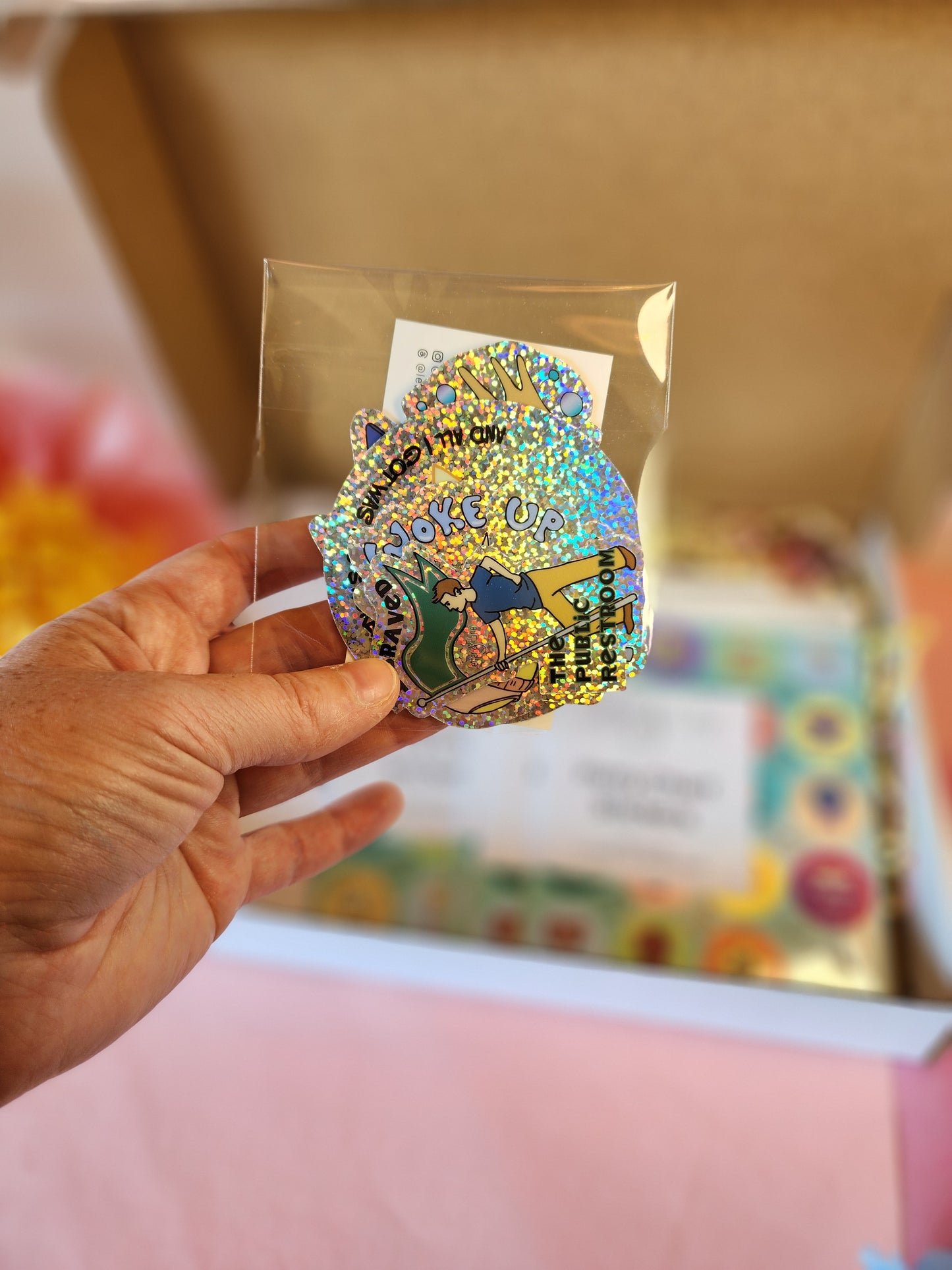 Hand holding a small clear bag containing five glitter potty stickers from the Potty Training Kickstart Kit.