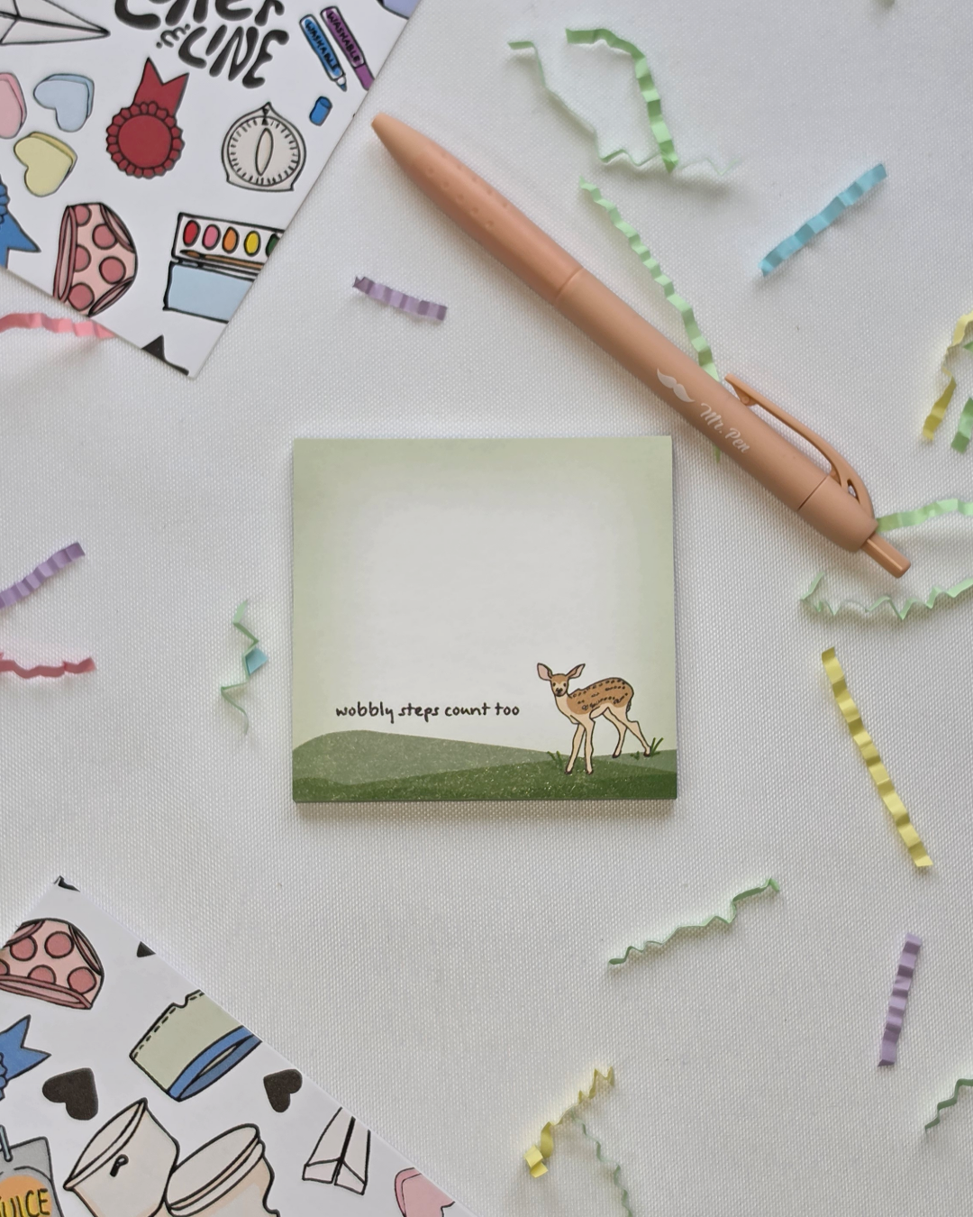 Wobbly Steps Count Too deer illustrated Post-it Note pad styled with a pen and colorful paper confetti on a white background