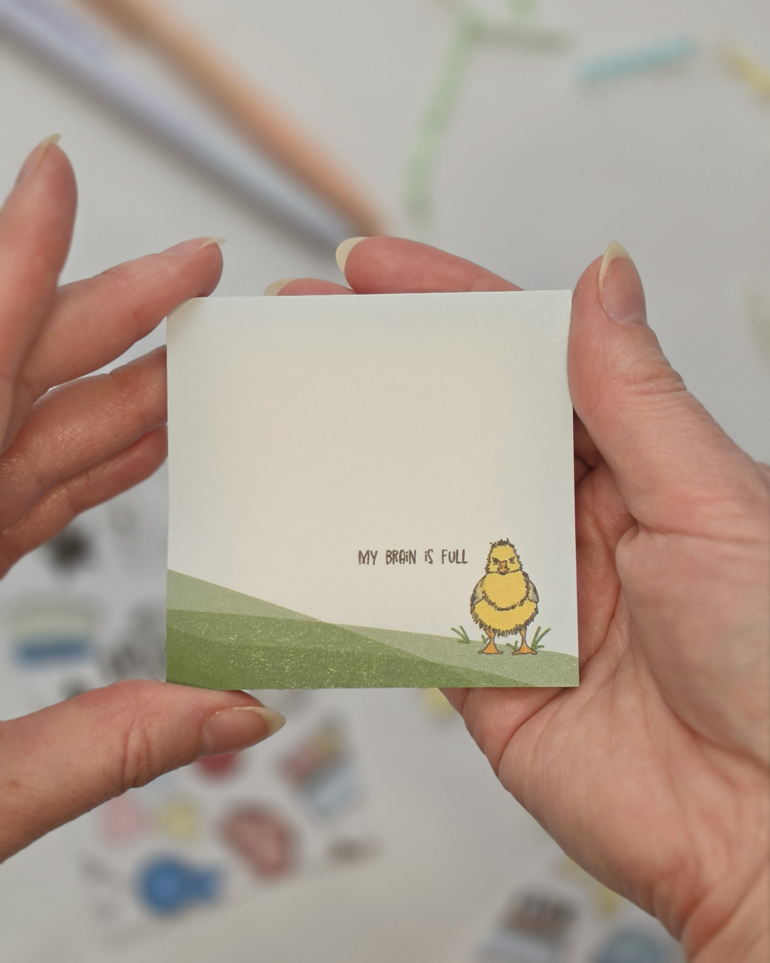 Hand holding My Brain is Full duck illustrated Post-it Note pad showing size and scale