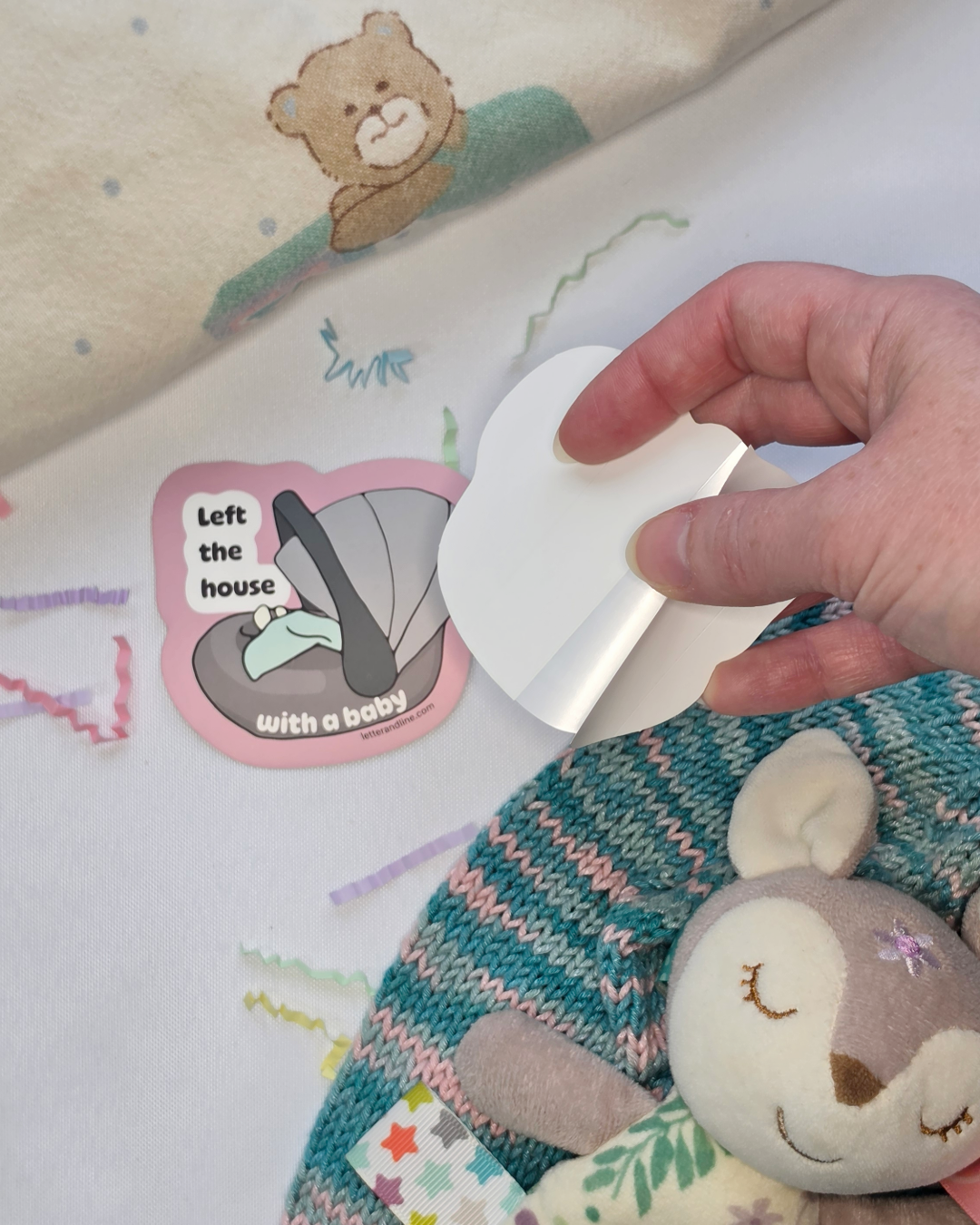 Left the House with a Baby milestone sticker shown with split backing being peeled for easy application