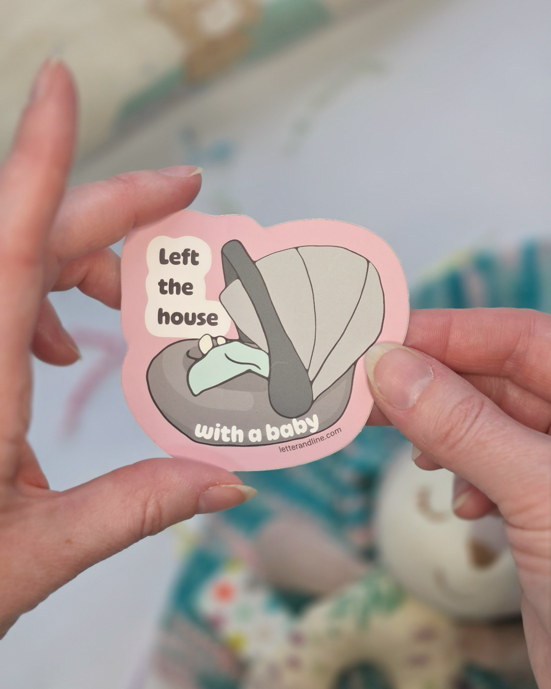Hand holding Left the House with a Baby new parent milestone sticker showing size and detail