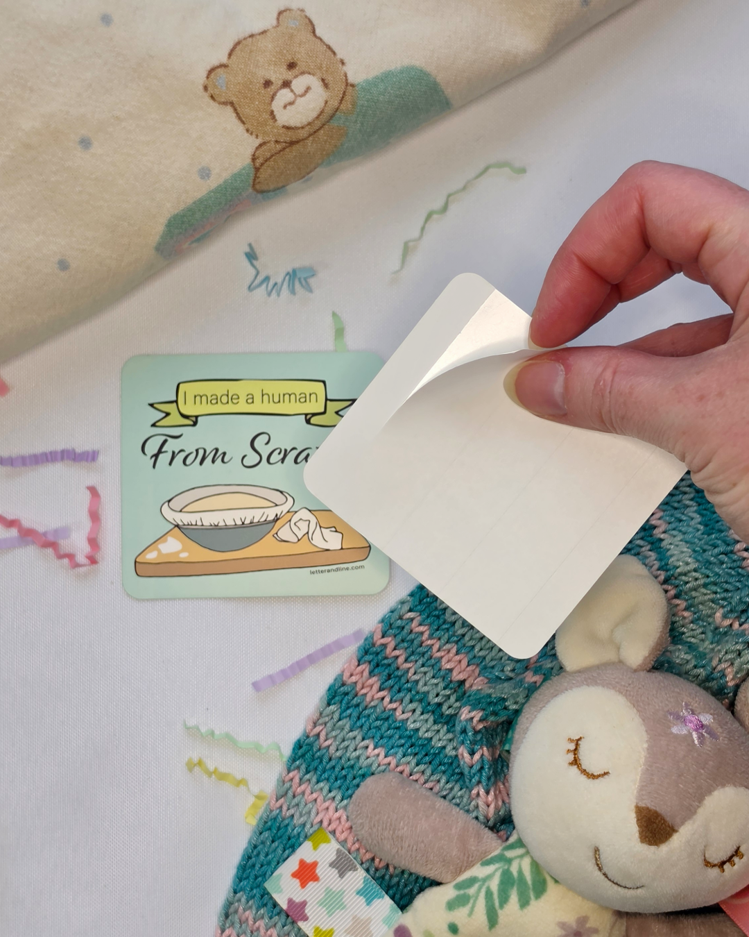 I Made a Human From Scratch milestone sticker shown with split backing being peeled for easy application