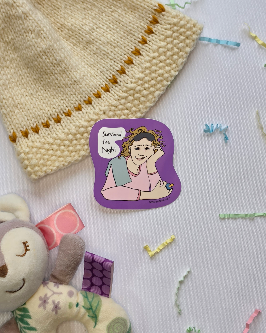 Survived the Night milestone sticker styled with a knit baby hat and colorful confetti and baby items