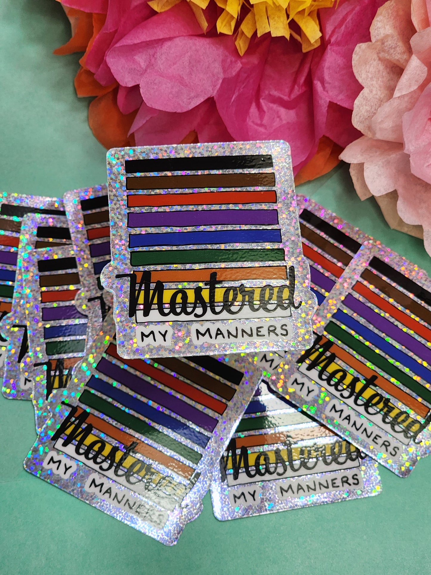 scattered group of “Mastered my Manners” glitter stickers, angled to catch holographic shine