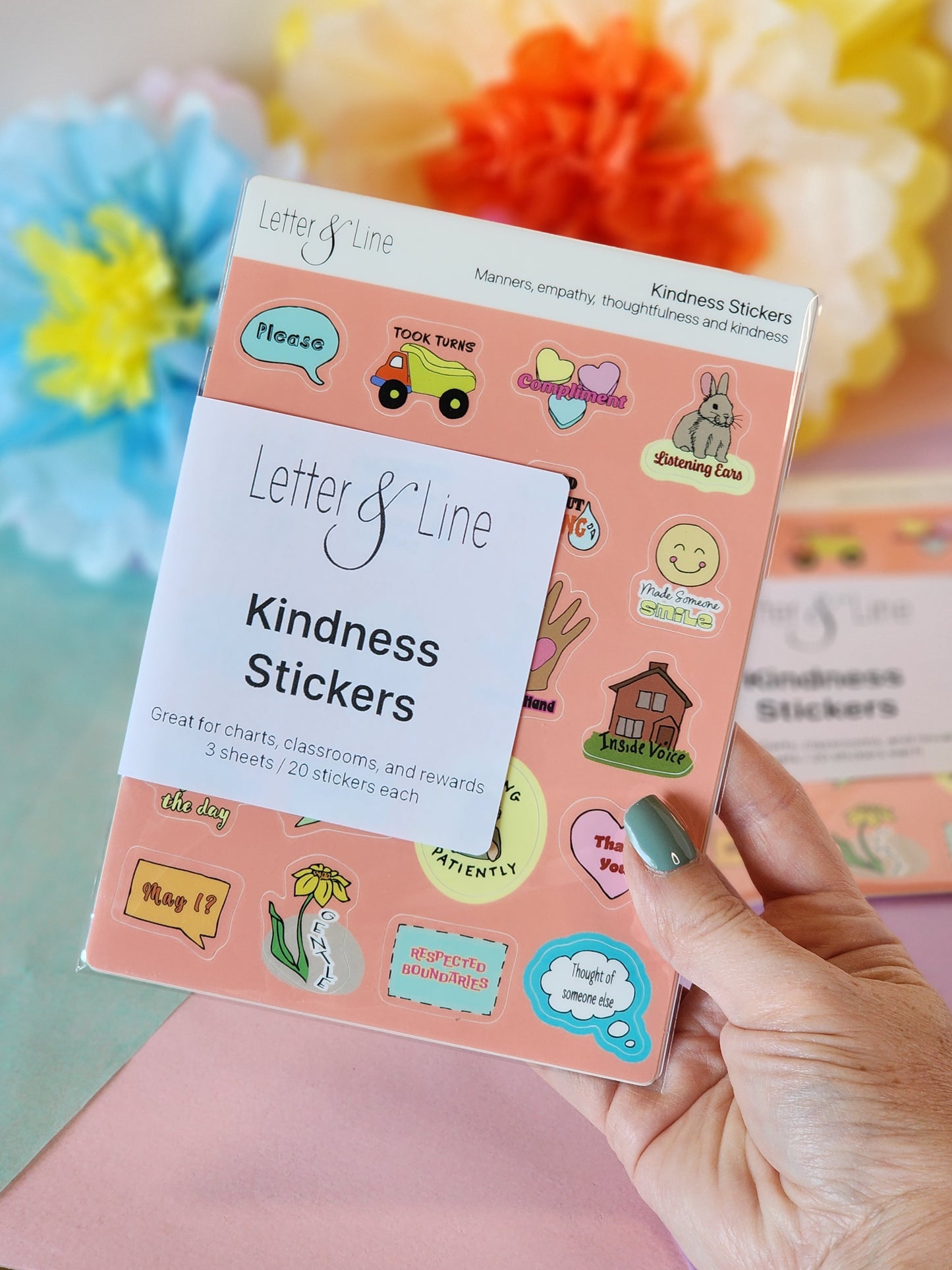 Kindness sticker sheet set for toddler behavior reinforcement shown with packaging and colorful paper flowers in the background.