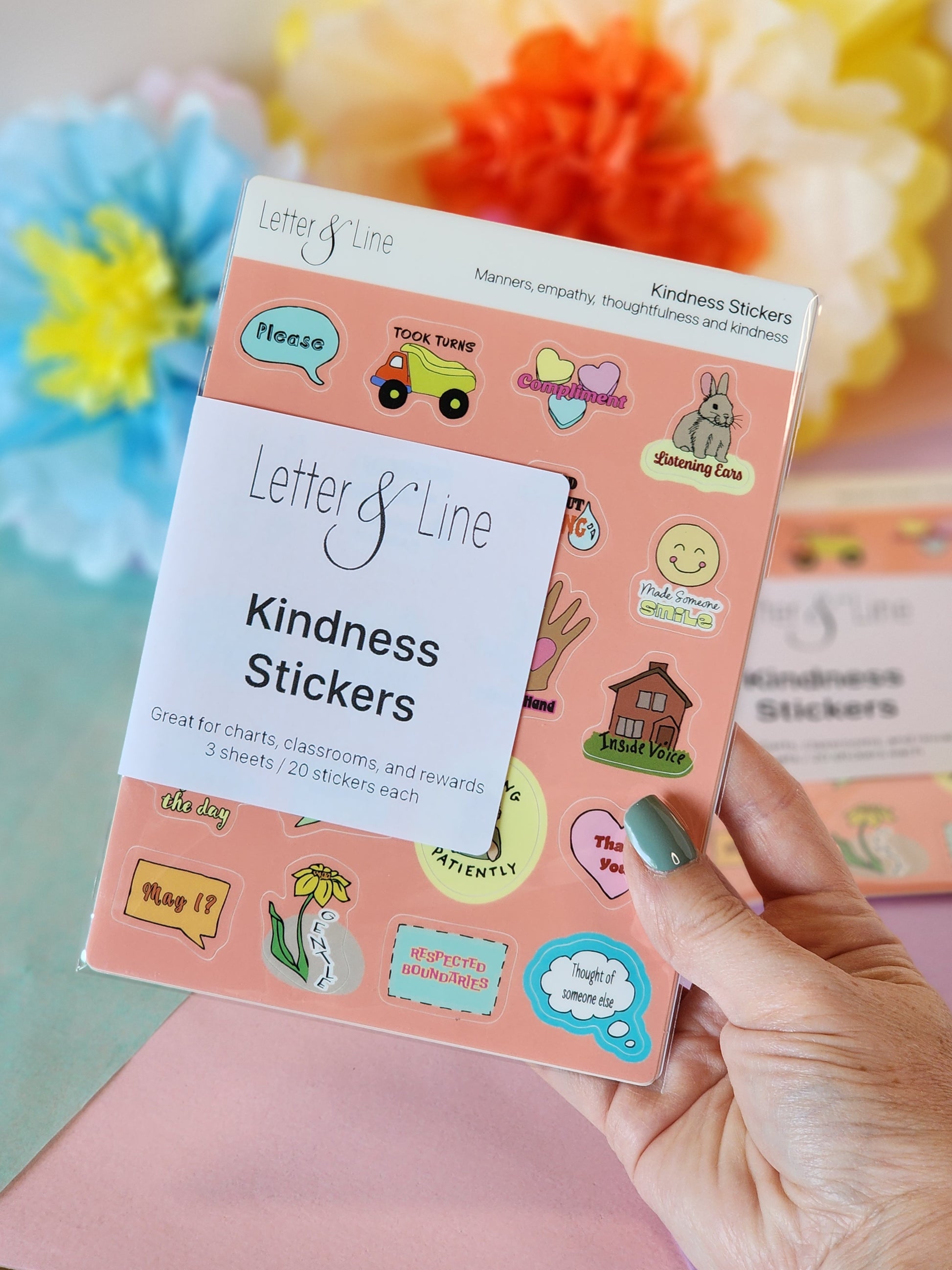 Kindness sticker sheet set for toddler behavior reinforcement shown with packaging and colorful paper flowers in the background.