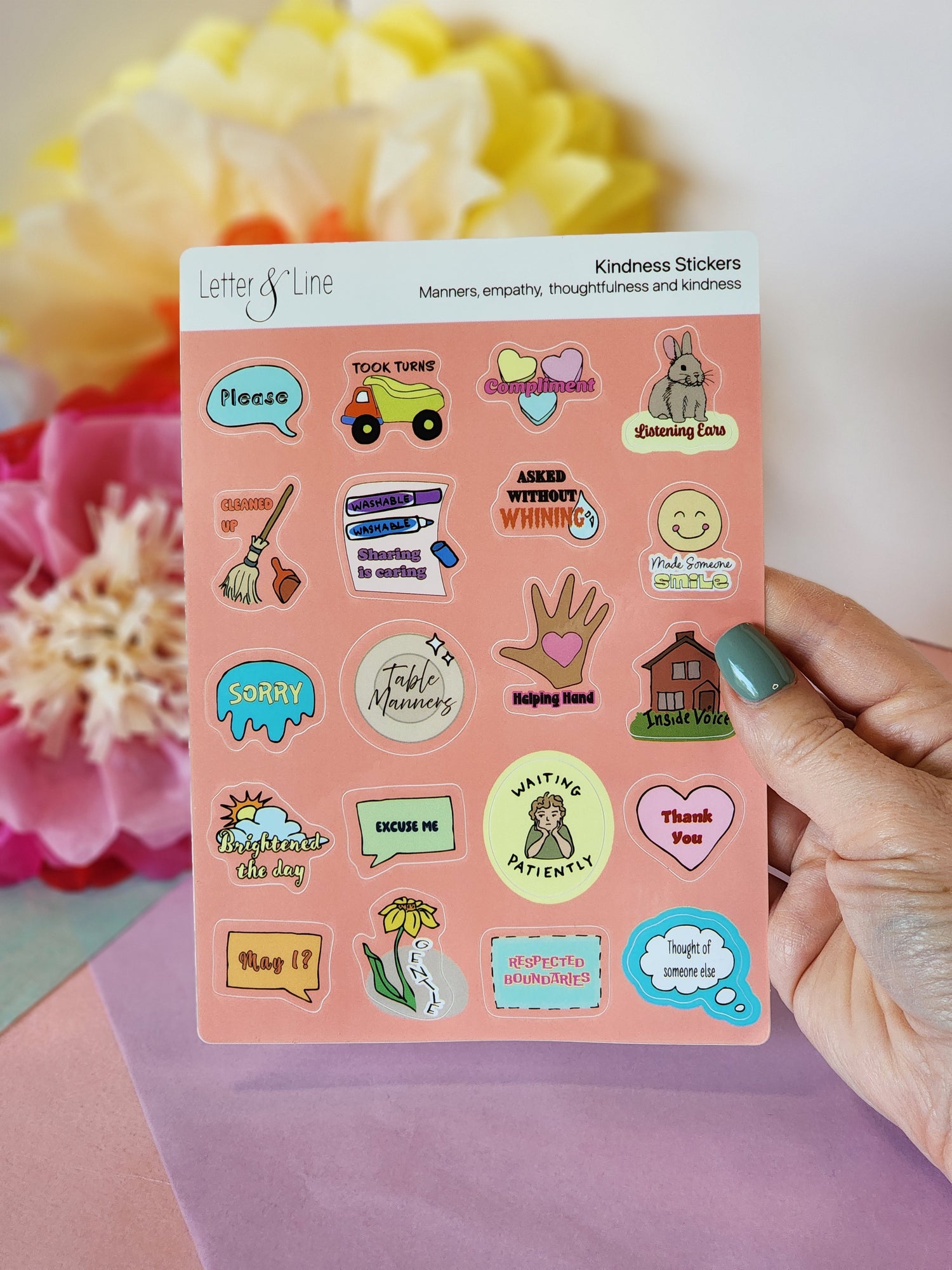 Hand holding a kindness sticker sheet for toddlers with 20 unique manners-themed designs to encourage positive behavior, shown against a floral backdrop.