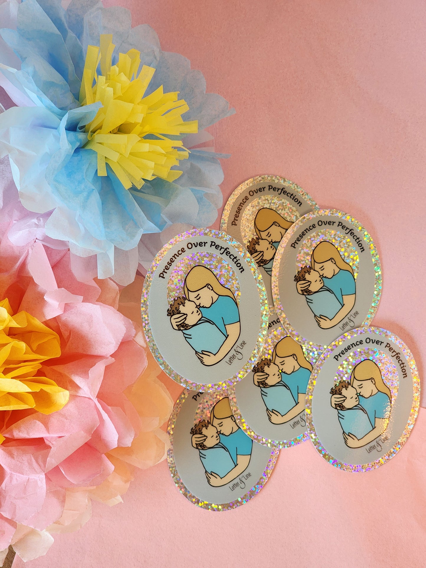 Six “Presence Over Perfection” stickers arranged in a gentle curve on a pink surface with bright pastel tissue flowers.