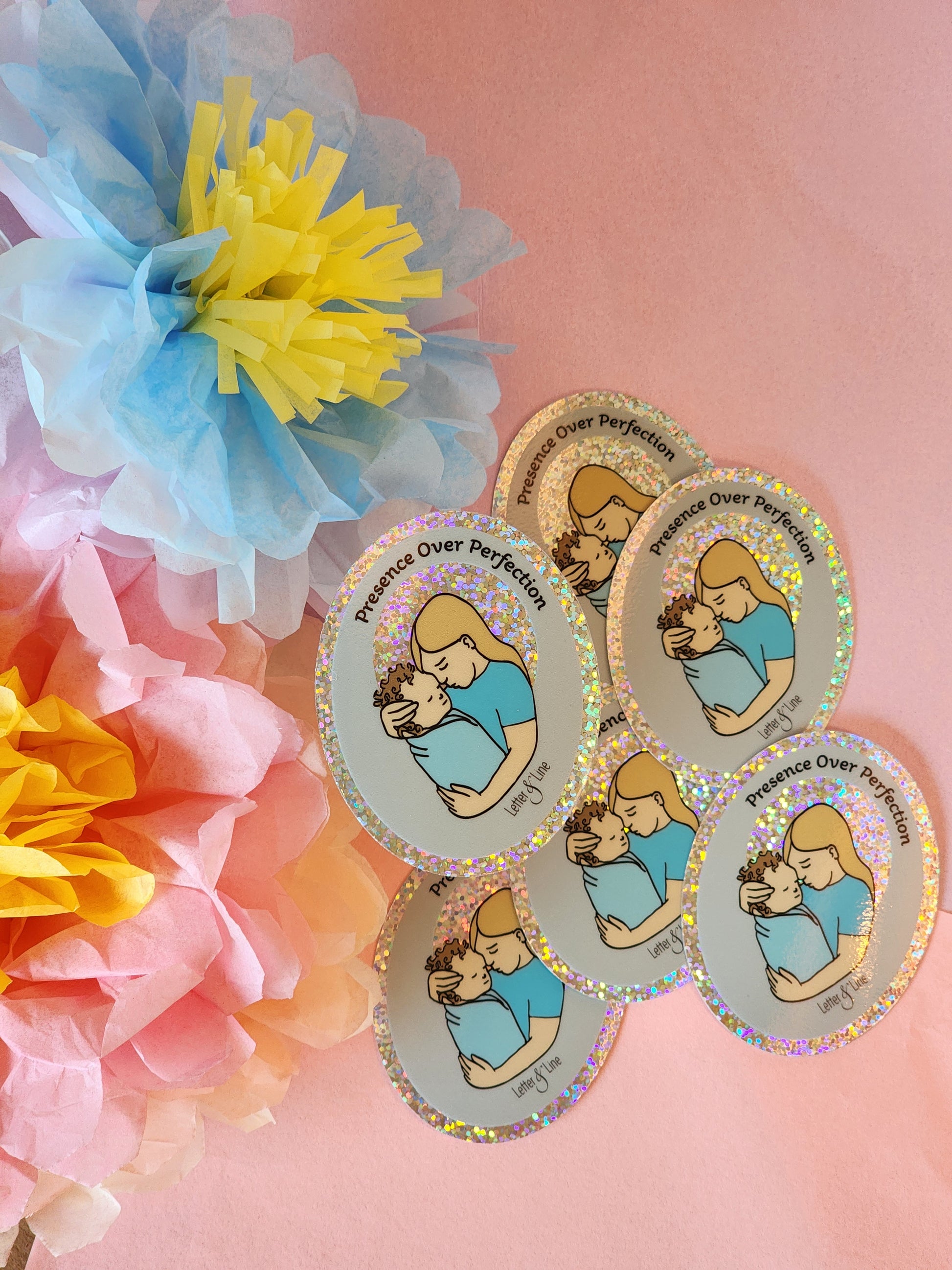 Six “Presence Over Perfection” stickers arranged in a gentle curve on a pink surface with bright pastel tissue flowers.